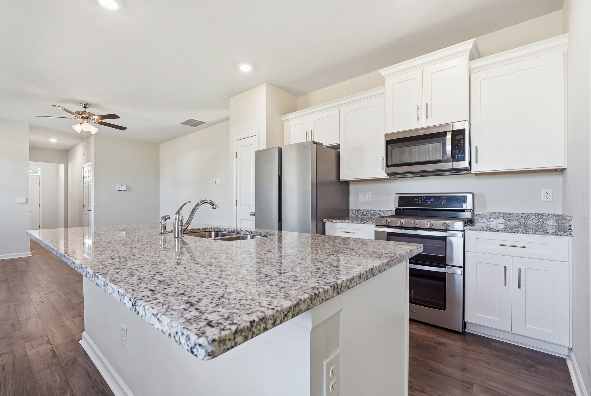 White kitchen with a large granite island and stainless steel appliances