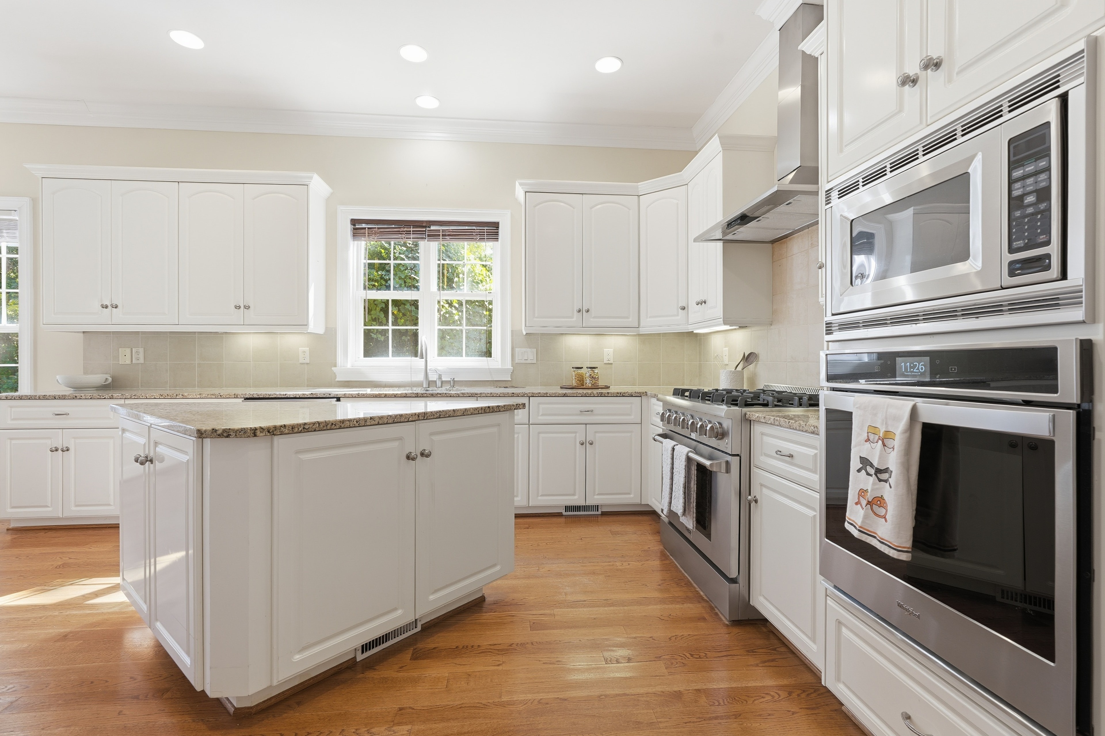 White kitchen island with a gas range and double wall ovens