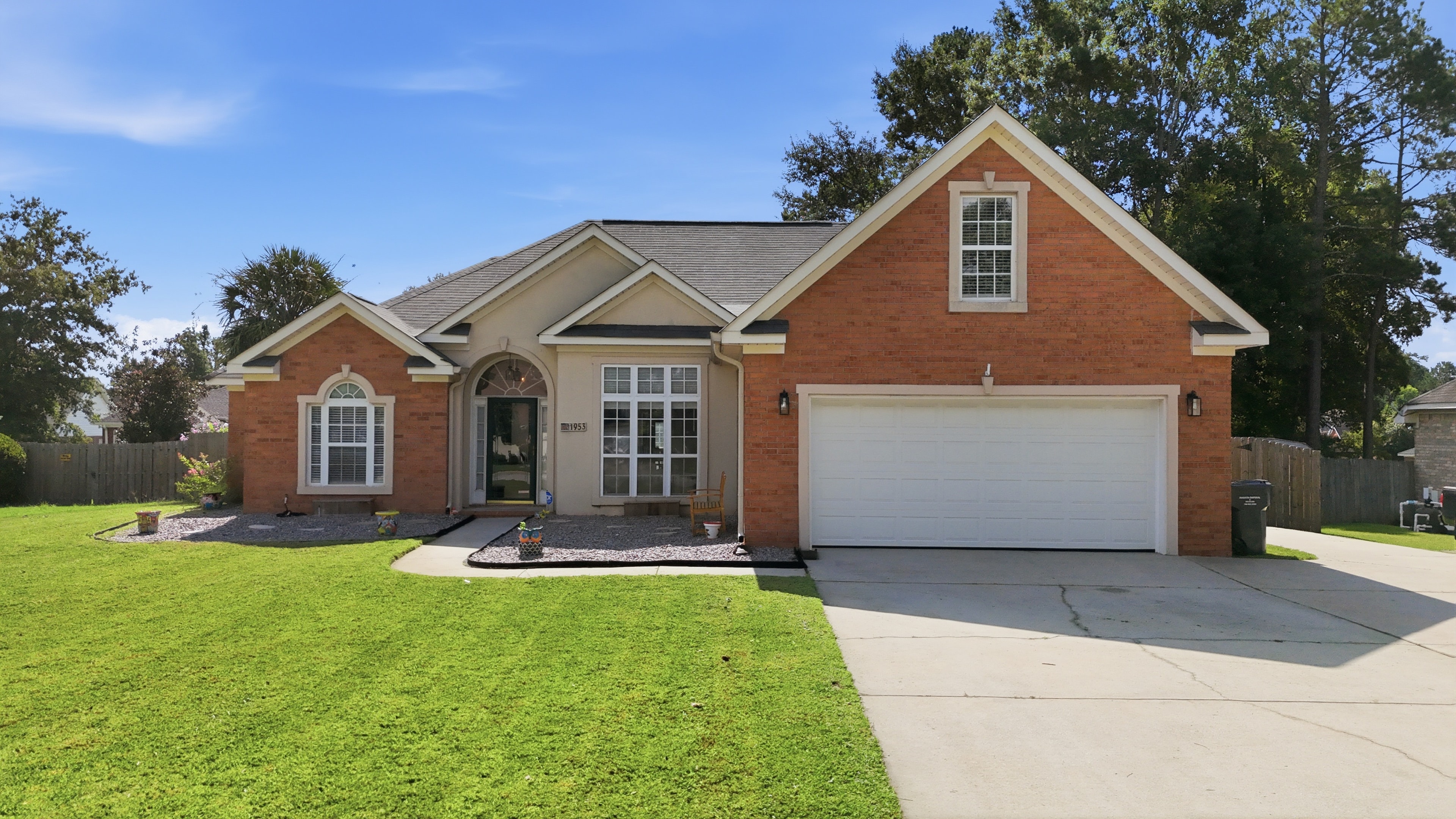Brick ranch home with a two car garage and a wide front lawn