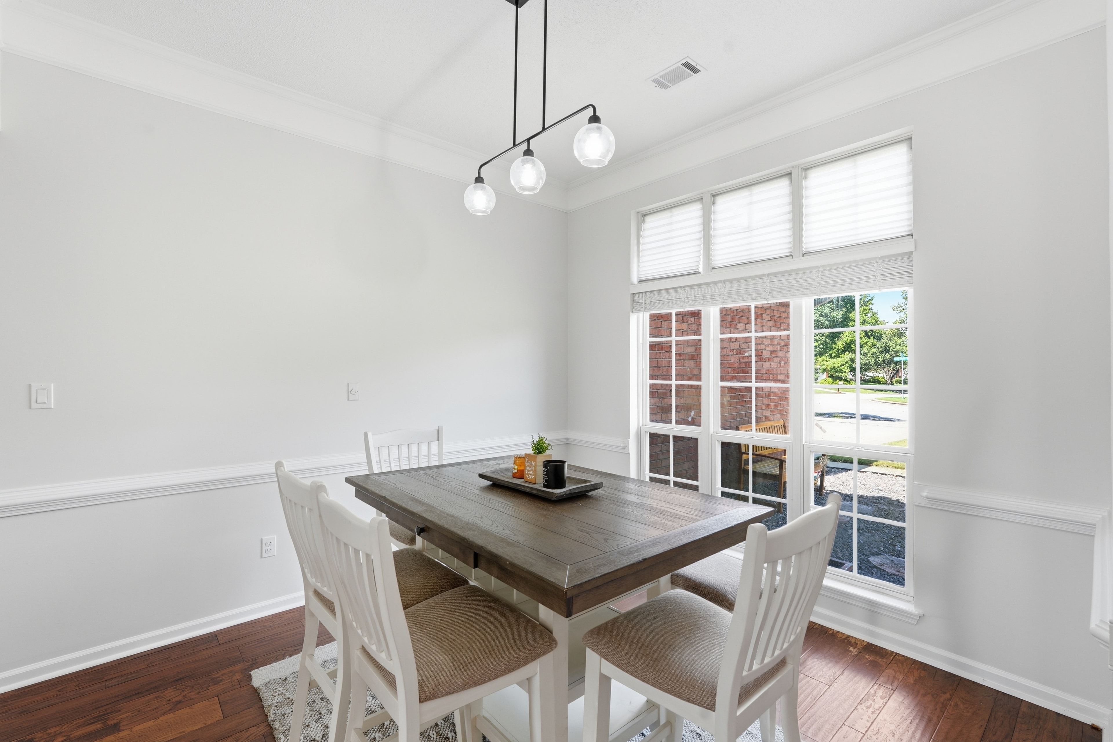 Dining room with white walls, a farmhouse table, and a three globe pendant