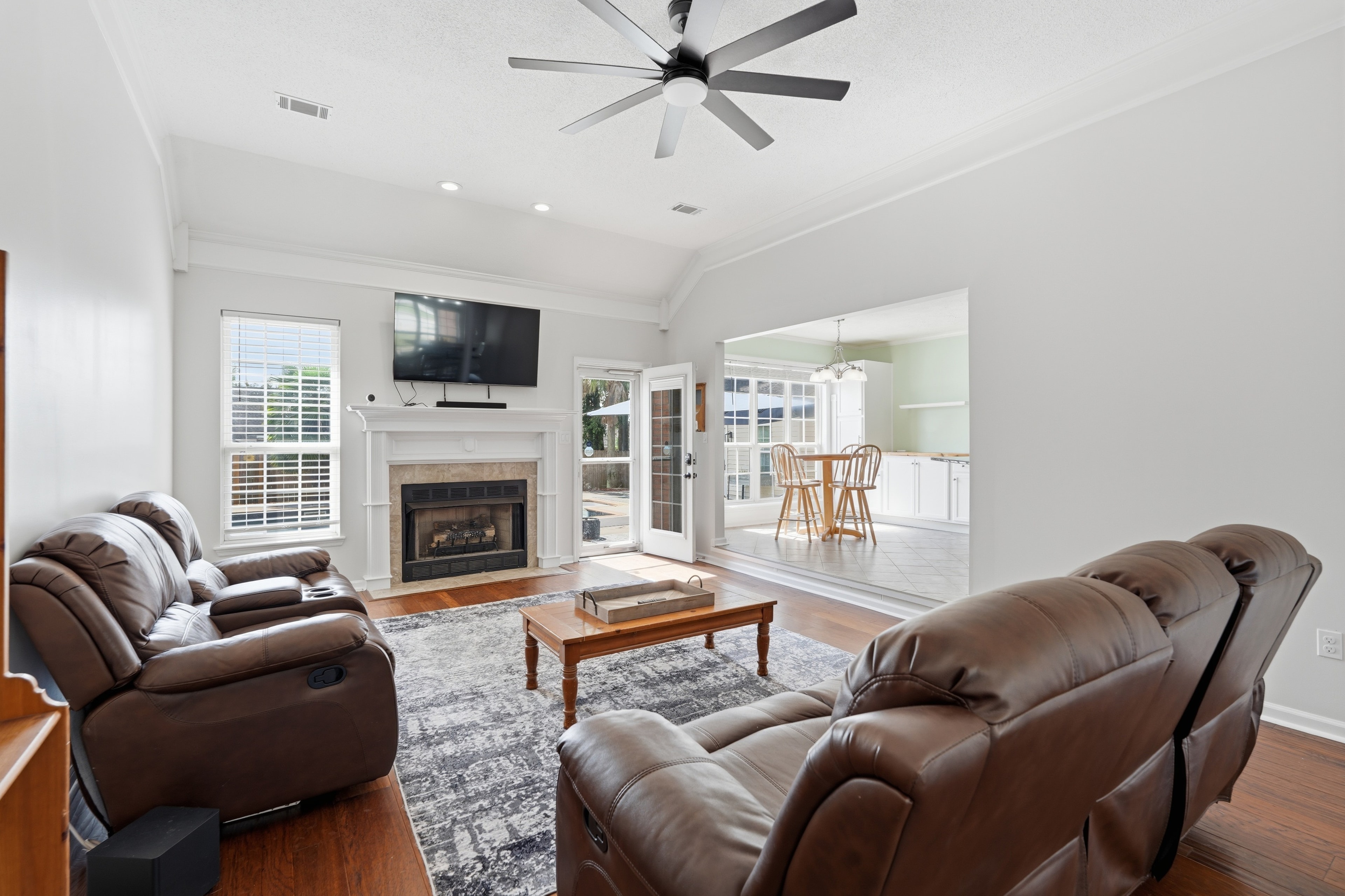 Living room with a fireplace, leather recliners, and a ceiling fan